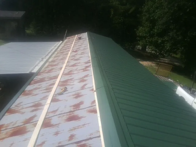 Old rusted panels beside newly installed green metal roofing — Wind Damage Roof Repair by Roofing Brothers in South Bend