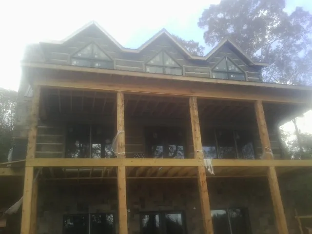 Dormers and porch framing on a large log home under construction — Roof Coating work by our crew in South Bend
