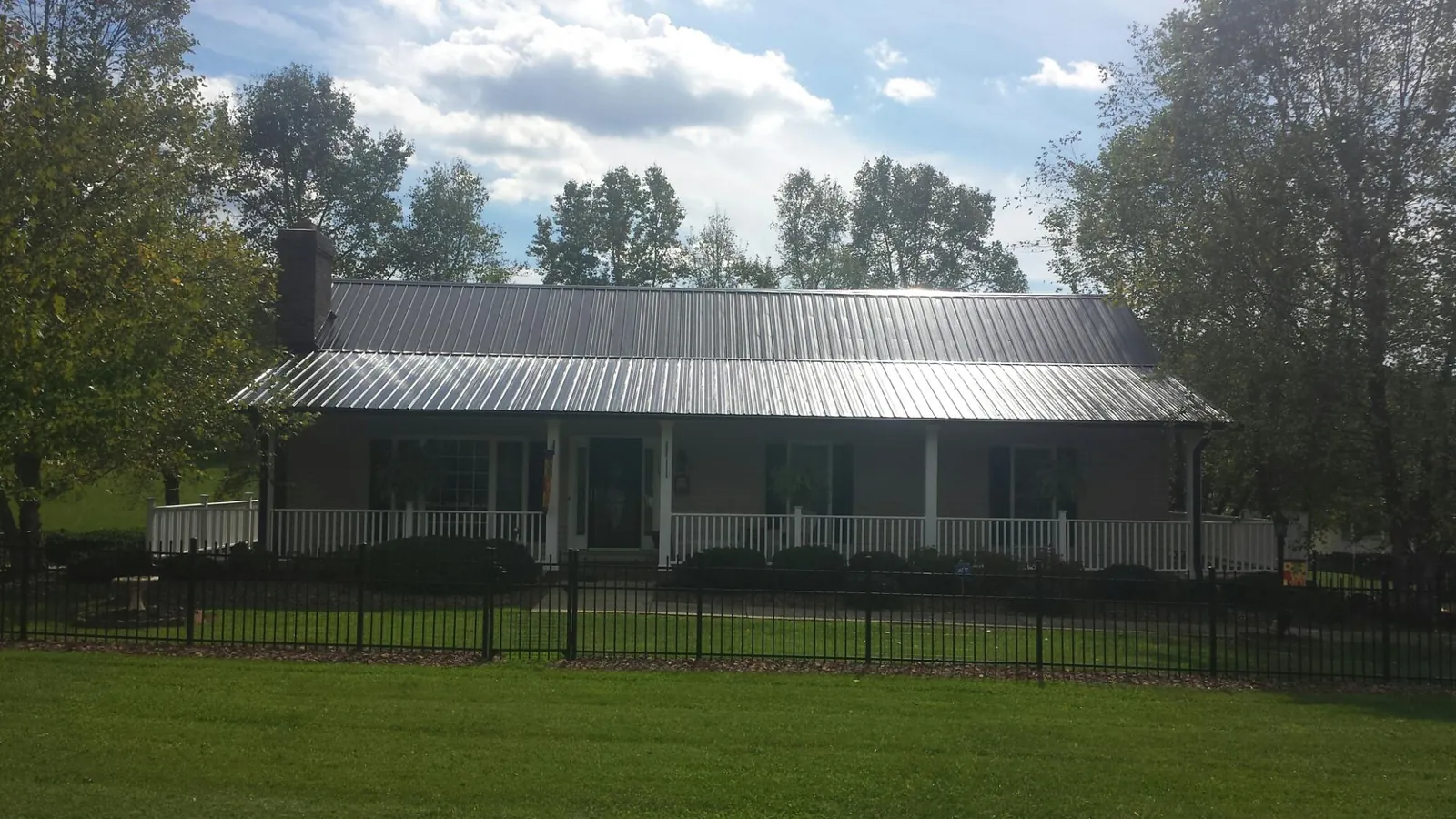 Gray metal roof on a brick ranch with a full width front porch — Gutter Guard Installation work by our crew in South Bend