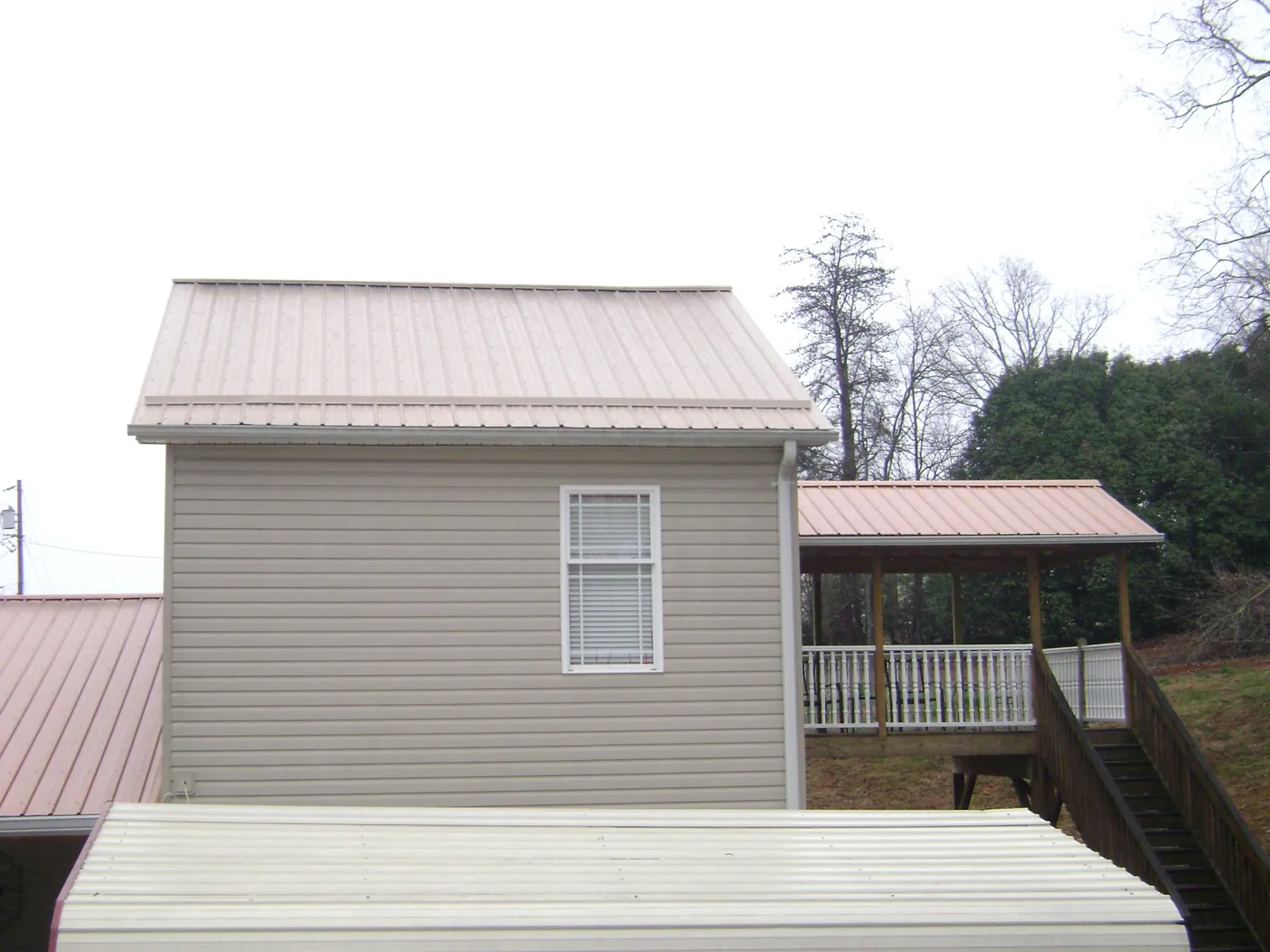 Tan metal roofs on a two story addition and attached porch, from a Roof Replacement job in South Bend