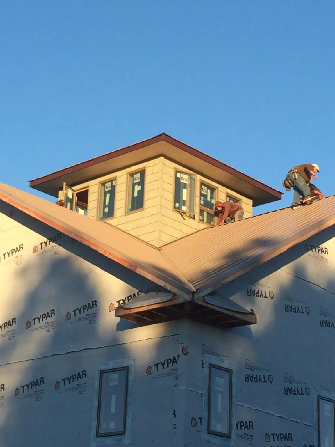 Roofers working around a rooftop cupola on a new metal roof at sunset — Roof Waterproofing in South Bend by Roofing Brothers
